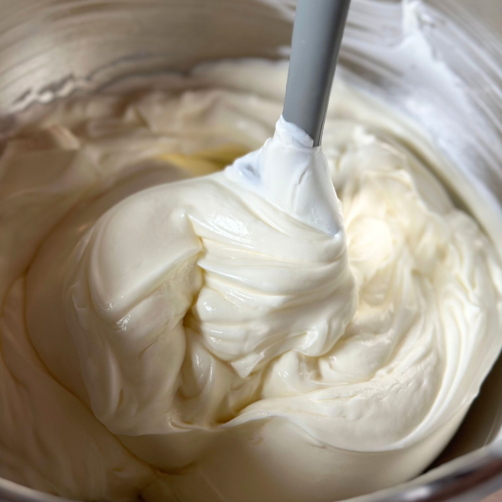 Handmade vegan skincare cream being whipped to a smooth texture in a stainless steel bowl.