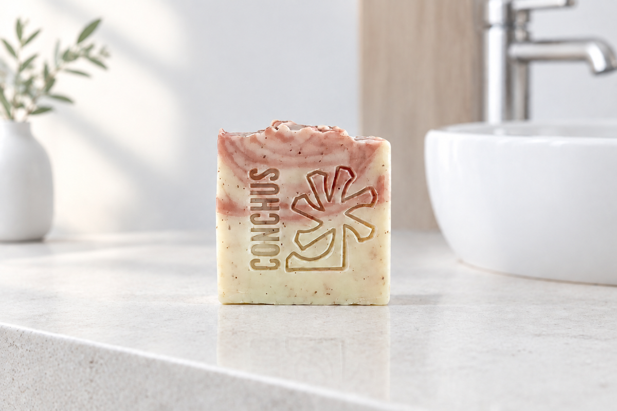 CONCHUS Cherry handmade exfoliating soap bar in soft peach tones, styled with botanicals on wood and stone