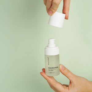 Hand holding BEAUTYPRO Niacinamide serum pump bottle — lightweight daily serum for oily and congested skin